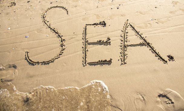 L'iscrizione "mare" nella sabbia e l'onda che corre sulla parola
. - Foto, immagini