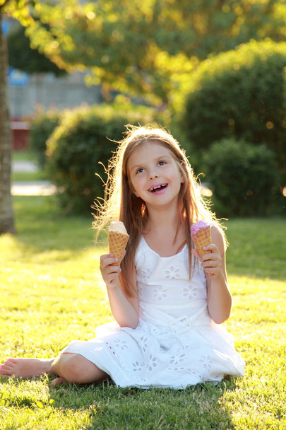 夏の公園でアイスを食べて笑顔の子. - 写真・画像