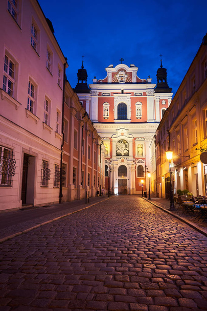 die gepflasterte Straße und die Fassade der Barockkirche bei Nacht in Posen - Foto, Bild