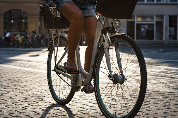 pernas de um ciclista pedalando em uma ponte de pedra da cidade velha em
  - Foto, Imagem