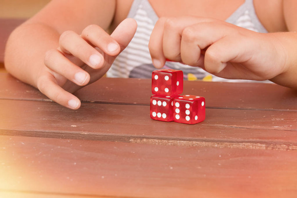 Dívčí ruce si hrají se čtyřmi červenými kostkami - Fotografie, Obrázek