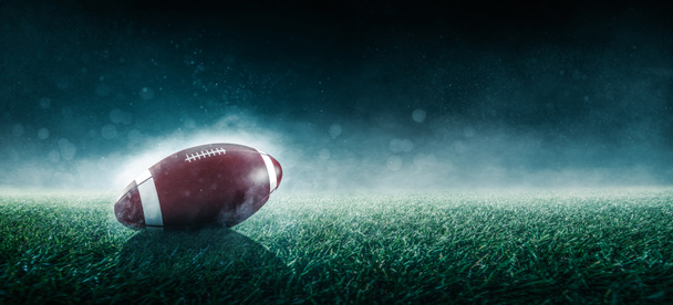 煙と緑の芝生のフィールド上のアメリカンフットボールボール - 写真・画像