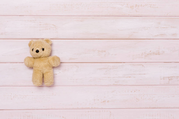 Small teddy bear on pink wooden background, top view - Photo, Image