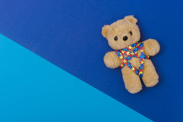 Journée mondiale de sensibilisation à l'autisme, concept de soins de santé mentale avec ours en peluche et motif de puzzle en ruban. Sur fond bleu
 - Photo, image