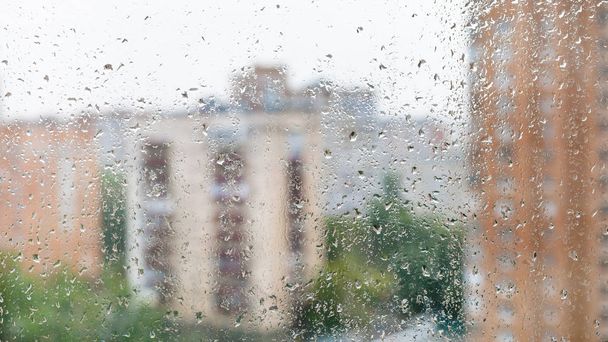 rain drops on window glass and blurred cityscape - Фото, изображение