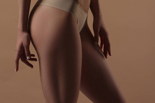 Thin young woman in underwear on beige background - Fotoğraf, Görsel