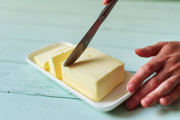 woman hands cutting butter on a lime wooden desk - Fotoğraf, Görsel