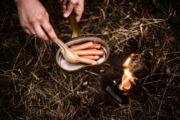 Worstjes worden gebakken over een open vuur in een pan - Foto, afbeelding