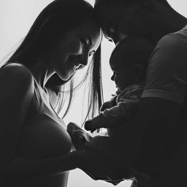 Imagen en blanco y negro de una pareja joven con un bebé recién nacido en sus brazos
 - Foto, imagen