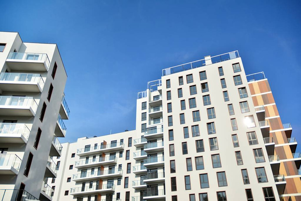 Kortárs lakóépület külseje nappal. Modern apartman épületek egy napsütéses napon, kék égbolttal. Modern lakóház homlokzata - Fotó, kép