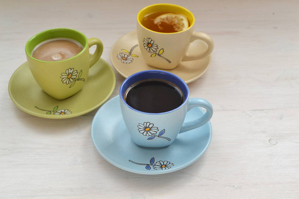 Café, cappuccino e chá em xícaras coloridas na mesa pobre
 - Foto, Imagem