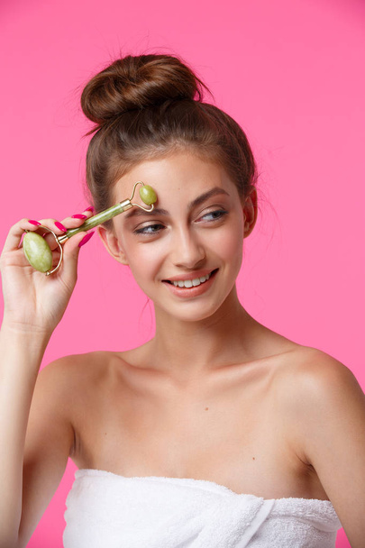 Mujer aplicando rodillo de jade para masaje facial
 - Foto, imagen