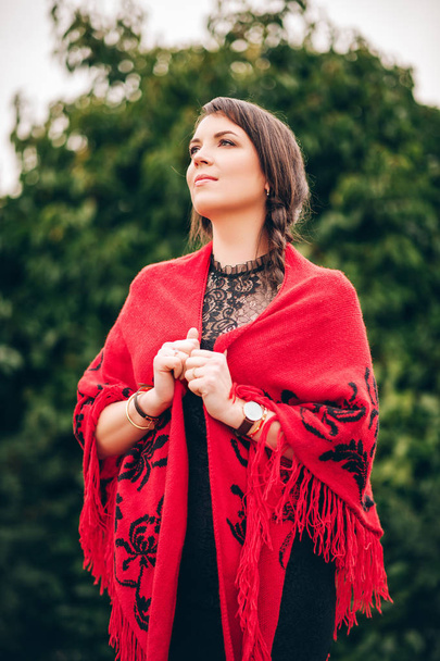Portrait extérieur de jolie jeune femme brune couverte de châle rouge
 - Photo, image