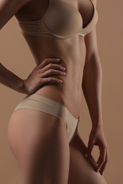 Thin young woman in underwear on beige background - Foto, Bild