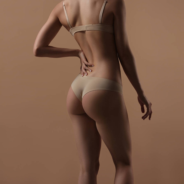 Thin young woman in underwear on beige background - Valokuva, kuva