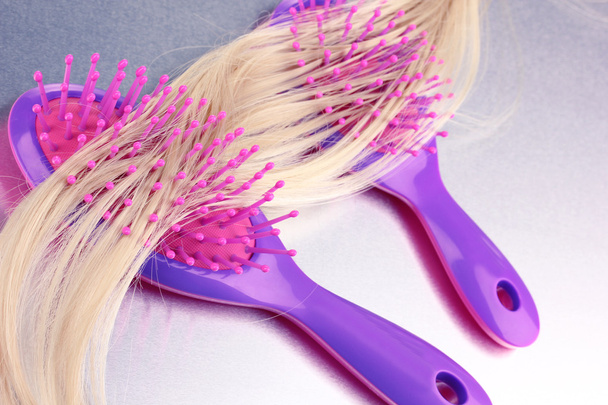 Blond curls brushing two combs on metalic background - Φωτογραφία, εικόνα