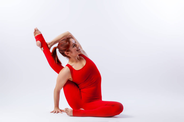 Hermosa mujer delgada en overoles deportivos haciendo yoga, de pie en una pose de equilibrio asana Garza Pose sobre fondo blanco aislado. El concepto de deporte y meditación. Entrenamiento para estiramientos y yoga
 - Foto, imagen