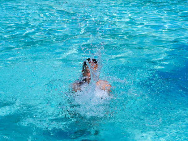 Pretty athletic sun tanned girl splashing in a swimming pool on vacation - Φωτογραφία, εικόνα
