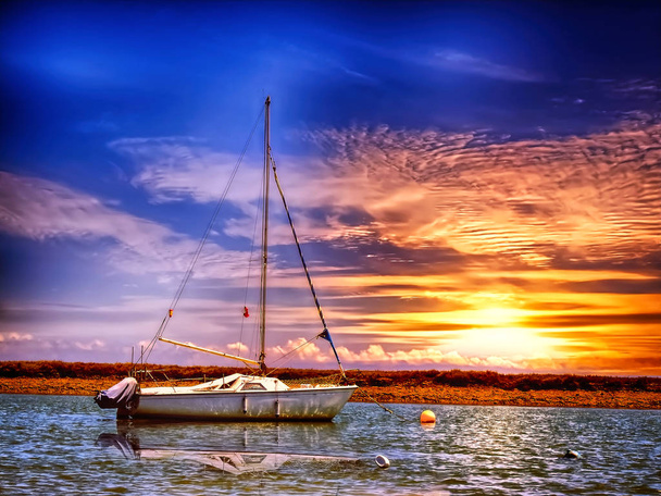 Gün batımında suda yüzen yelkenliolmayan bir tekne - Fotoğraf, Görsel