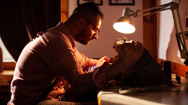 Europese man naait kleren in zijn naaiatelier thuis. - Foto, afbeelding