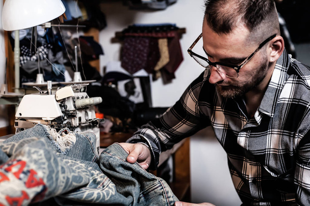 Homme européen coud des vêtements dans son atelier de couture à la maison
. - Photo, image