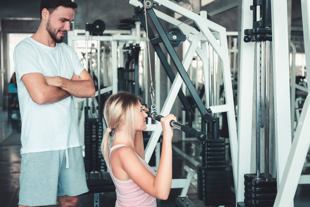 Portré gyönyörű nő gyakorolja képzés testépítő gép Fitness Club., vonzó a sportos lány doing dolgozó ki vele tréner az edzőteremben, egészséges és sport életmód koncepció. - Fotó, kép