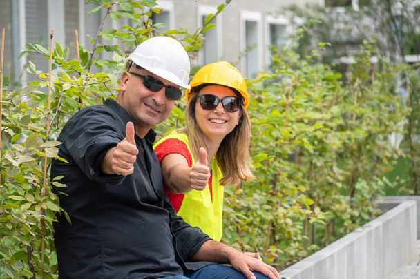 Trabajadores de la construcción alegres y exitosos posando mostrando un gesto de pulgares hacia arriba. Al aire libre
 - Foto, imagen