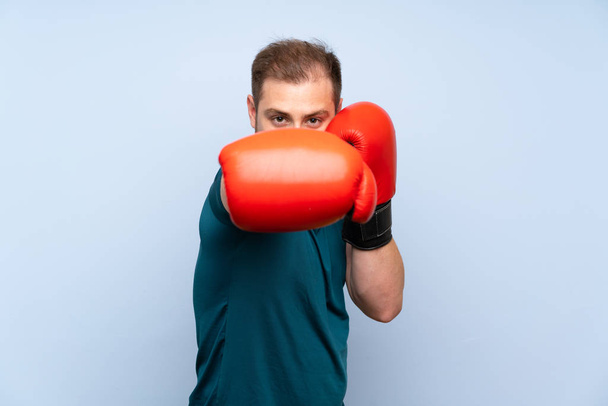 Blonde sport man over blue wall with boxing gloves - Photo, Image