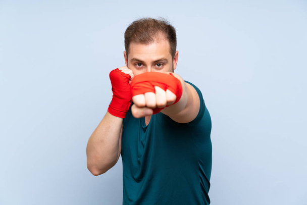 Blonde sport man over blue wall in boxing bandages - Fotografie, Obrázek
