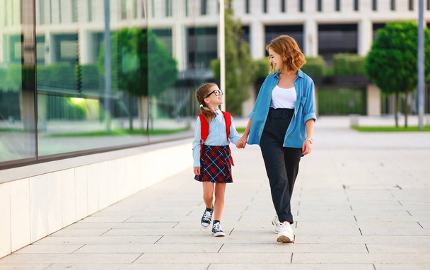 first day at school. mother leads  little child school girl in f - 写真・画像