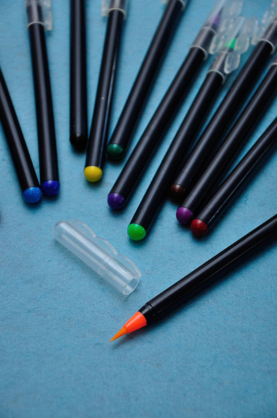 Μια πορτοκαλί πένα με το υπόλοιπο εκτός εστίασης σε μπλε φόντο - Φωτογραφία, εικόνα
