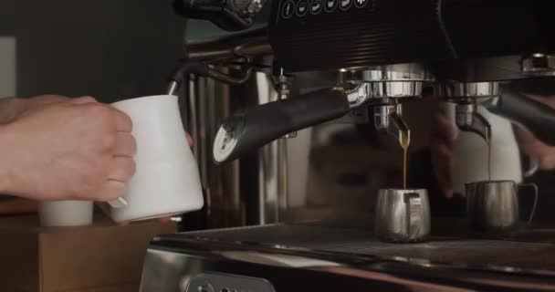 Αγνώριστη μπαρίστα που κρατάει Pitcher and Steaming Milk. Χύνοντας ροή καφέ από επαγγελματική μηχανή σε μεταλλικό κύπελλο. Διαδικασία για την παρασκευή καφέ στη σύγχρονη μηχανή από την αρχή μέχρι το τέλος στην καφετέρια  - Πλάνα, βίντεο