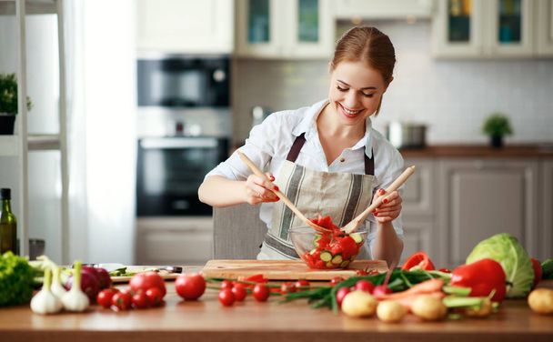 mulher feliz preparando salada de legumes na cozinha
 - Foto, Imagem