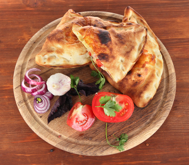Pizza calzones on wooden board on wooden table - Photo, image