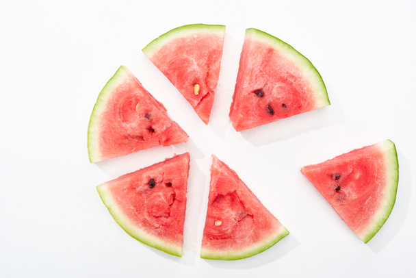 Top uitzicht van heerlijke sappige watermeloen plakjes in cirkel op witte achtergrond - Foto, afbeelding