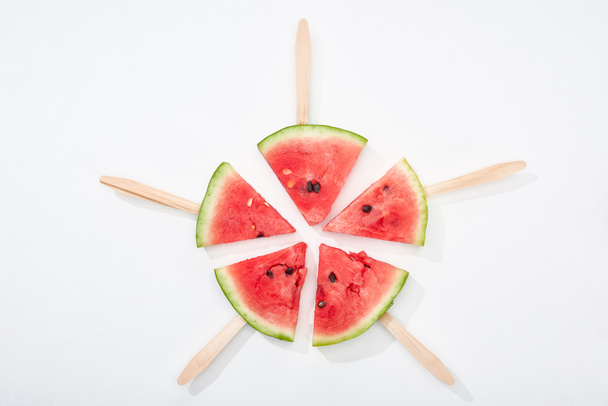 Draufsicht auf köstliche saftige Wassermelonenscheiben auf Holzstäben auf weißem Hintergrund - Foto, Bild