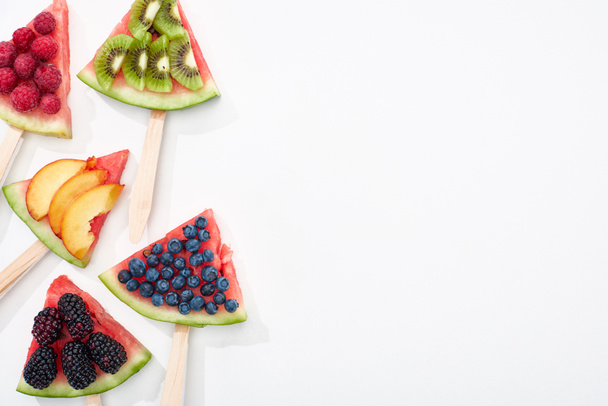 top view of tasty watermelon on sticks with seasonal berries and fruits on white background with copy space - Photo, Image