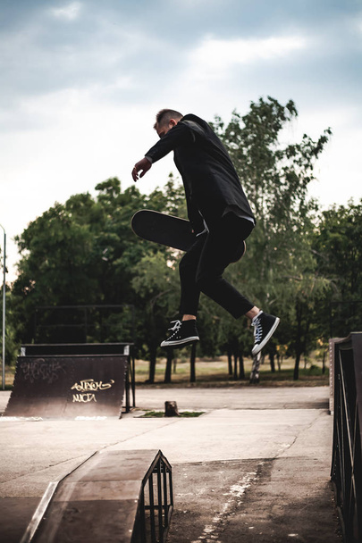 A guy in a classic black suit. Skateboarding, free life concept. - Fotoğraf, Görsel
