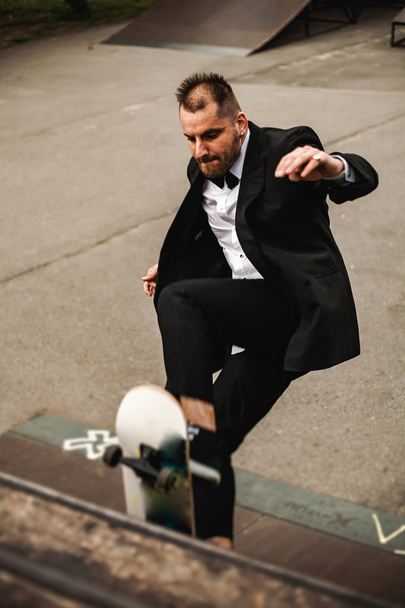 A guy in a classic black suit. Skateboarding, free life concept. - Photo, Image