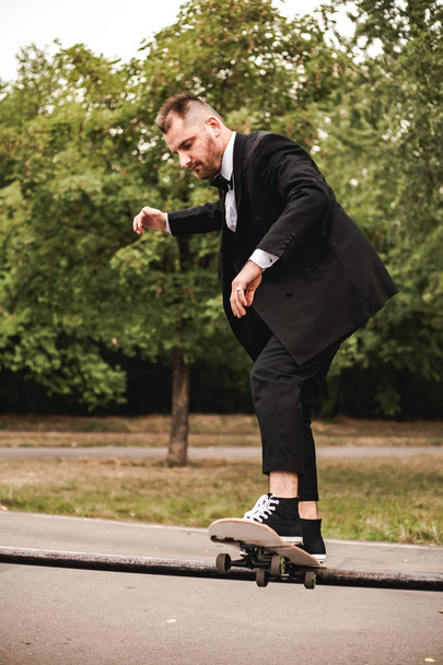 A guy in a classic black suit. Skateboarding, free life concept. - Foto, Bild