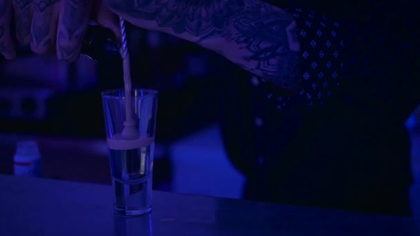 Close-up. The barman holding a bar spoon in hand and dipped it in an alcohol inside the glass. The bartender pouring the second level of alcohol in the shot with a spoon. The man take away the spoon. - Felvétel, videó