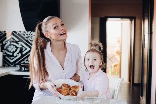 Gelukkige moeder en dochter tonen gebakken wrongel beignet - Foto, afbeelding
