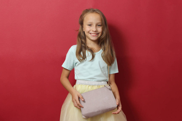 Petite joyeuse fille souriante vêtue de vêtements à la mode sur fond coloré. Vêtements pour enfants, mode pour enfants - Photo, image