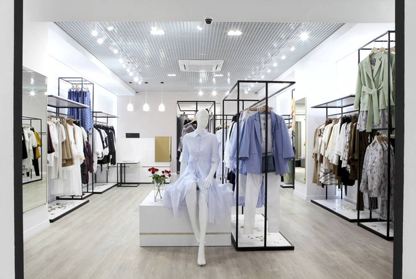 Interior of clothing store .Bright interior.Minimalistic style.Clothes hang on hanger.Trendy colors - Photo, Image