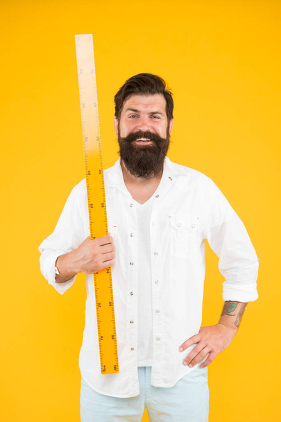 Man bearded hipster holding ruler. Measure length. Size tall and length. Big size. Measure and control. Geometry theorem. Actual size. School teacher. Small little big large. Does size really matter - Foto, imagen