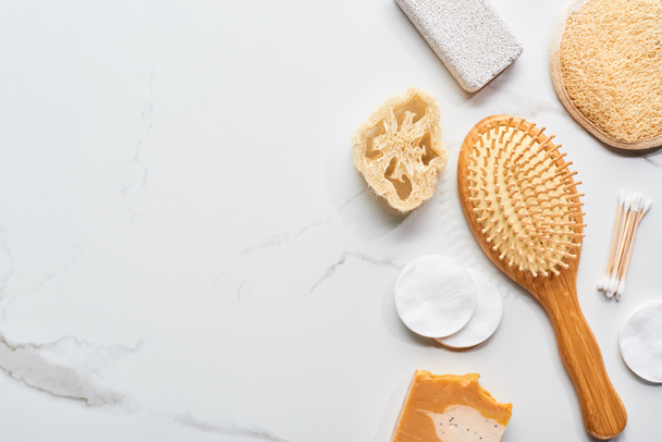 vista superior de almohadillas de algodón, orejeras, esponja y cepillo de pelo en la superficie de mármol
 - Foto, Imagen