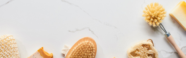 πανοραμική βολή από σφουγγάρι, βούρτσες σώματος, σαπούνι και σφουγγάρι μπάνιου σε μαρμάρινη επιφάνεια - Φωτογραφία, εικόνα