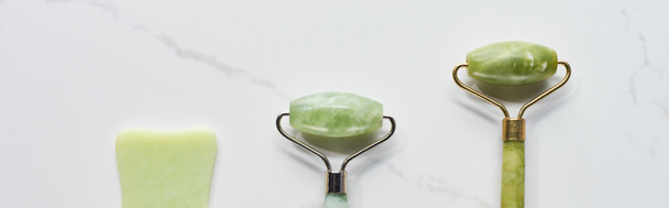 panoramic shot of facial spatula and massage rollers on marble surface - Photo, Image