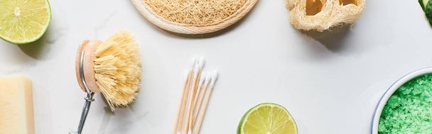 panoramic shot of ear sticks, body brush, loofah and fresh lime on marble surface - Photo, Image