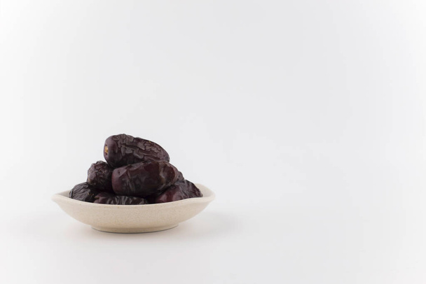 dry dark blue dates fruits in bowl plate, table with burlap napkin  - Fotó, kép